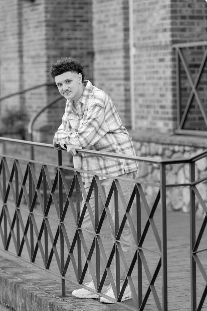 high school senior boy leaning on a metal fence