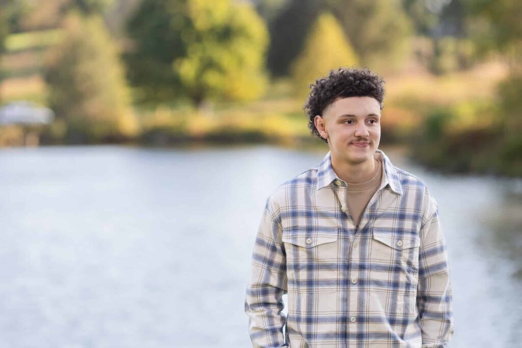 high school senior boy with a pond behind him