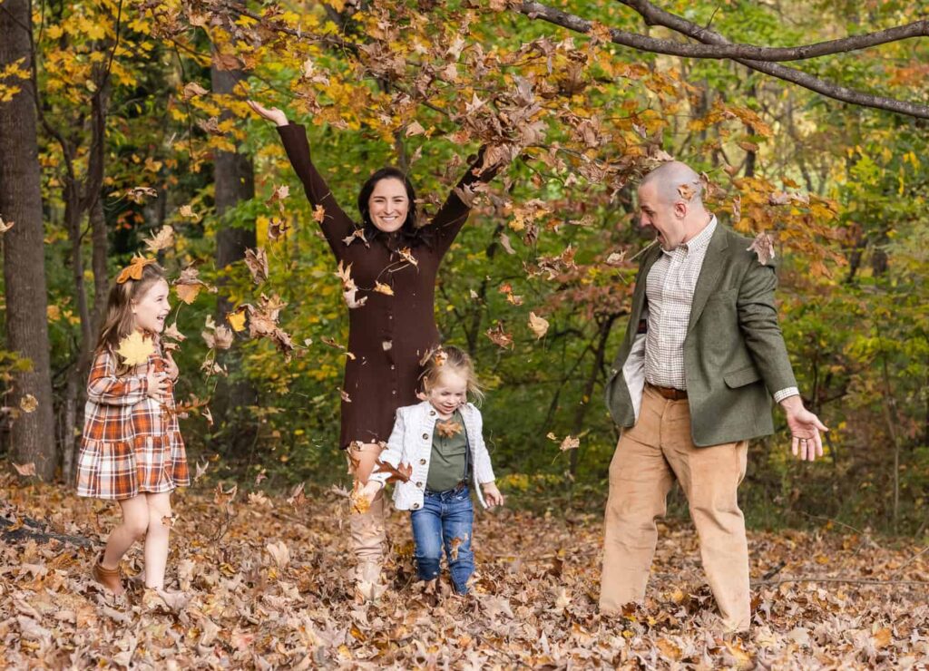 Family of 4 playing in fall leaves